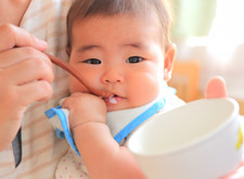 写真：離乳食を食べさせてもらう赤ちゃん