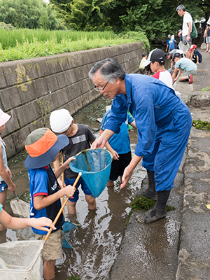 写真：用水を清掃する天野　武雄さんと子供たち