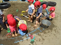 砂場でダイナミックに遊ぶ2歳児の写真