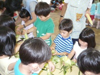 4歳児ぞう組がトウモロコシの皮むきをしている写真