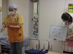 栄養士が子どもたちに調理前の衛生指導を行なっている写真