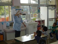4歳児ぞう組が調理活動の事前指導で栄養士の話を聞いている写真