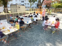 外で給食を食べる子どもの写真