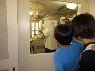 芋汁を作っている様子を調理室の窓から子どもがのぞいている写真
