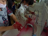 真っ赤になった手を洗う子どもの写真