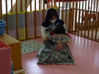 保育士に抱っこされて眠っている子どもの写真