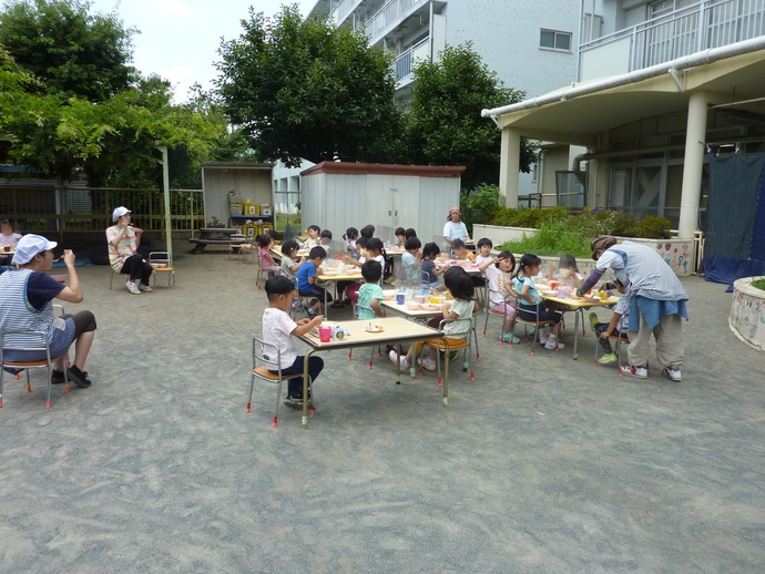 園庭で食事する子どもの写真