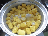 鍋でゆでているトウモロコシの写真