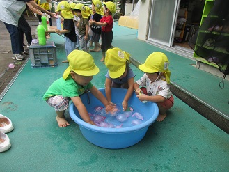 2歳児クラスのお友だちが水風船で遊んでいる様子の写真