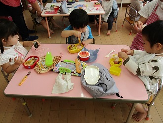 1歳児が遠足でお弁当を食べる様子の写真