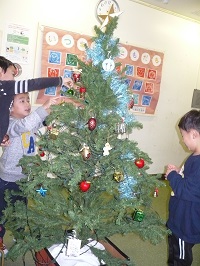 5歳児らいおん組の子どもたちが、クリスマスツリーの飾りつけをしている写真