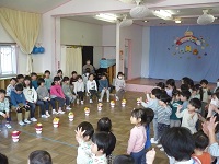 1歳児りす組と2歳児うさぎ組が5歳児らいおん組にお祝いの手遊びをしている写真