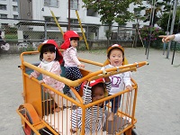 1歳児クラスがワゴン車に乗って園庭散歩をしている写真です。
