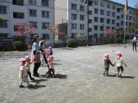 2歳児クラスが手を繋いで園庭を歩いている写真です。