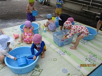 プールサイドで水遊びをする3歳児の写真
