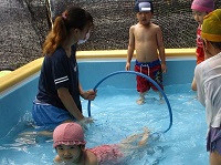 4歳児がプールでフープくぐりをしている写真です。