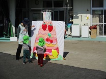 ケーキのパネルにフルーツを貼る4歳児の写真