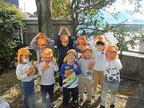 収穫したミカンを持った4歳児クラスの写真