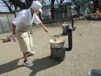 給食の先生がかまどで芋汁を作っている様子の写真