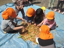 子どもたちが野菜の皮と土を混ぜている写真