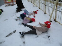 子どもが雪の上で転がる様子の写真