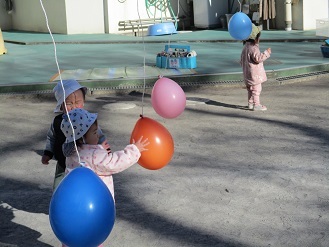 写真：お正月遊び　0歳児が風船羽根つきをしている様子