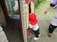 小屋をのぞき込んでいる1歳児の写真