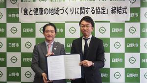写真：協定締結式で締結書を交わす大坪市長と黒田社長