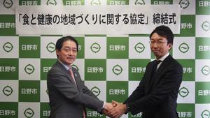 写真：協定締結式で握手を交わす大坪市長と黒田社長