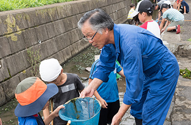 写真：用水を清掃する天野　武雄さんと子供たち