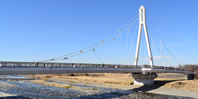 写真：青空を背景に浅川を渡るふれあい橋