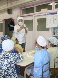 栄養士さんのよるピザの作り方の説明を聞いている写真