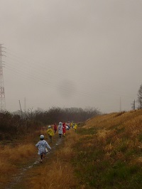 雨の浅川土手を歩いている写真