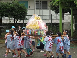 五歳児がお神輿を担いで歩いている写真