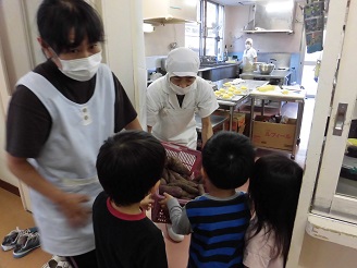 3歳児（こあら組）さんが洗ったさつま芋を給食室に届けている写真