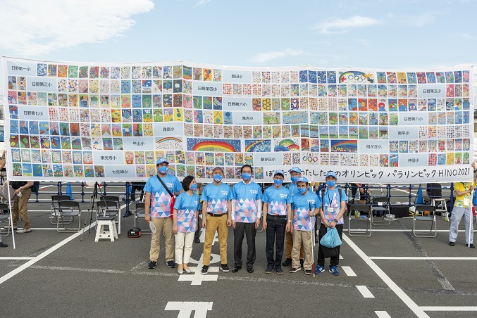 全小学校絵画作品の横断幕をバックに大坪市長と光バンドの集合写真
