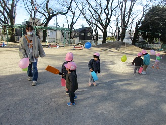 風船羽根つきを楽しむ1歳児の様子の写真