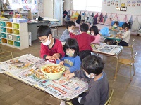 4歳児ぞう組が土づくりの為に野菜くずやみかんの皮をちぎっている写真