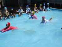 5歳児らいおん組が第八小学校のプールでビート板につかまって遊んでいる写真