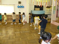 5歳児らいおん組がホールで輪になって盆踊りを踊っている写真