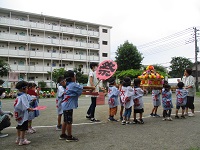 子どもたちがおみこしを担いで歩いている写真