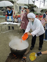 栄養士さんが鍋に食材を入れている写真