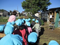 4歳児ぞう組の子どもたちがせせらぎ農園の方の話を聞いている写真