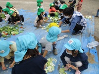 0歳児の子どもも参加して土を作っている写真です。