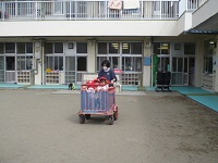 1歳児りす組がワゴン車で園庭を散歩している写真