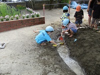 4歳児が川に水を流している写真です。