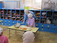 5歳児らいおん組の子どもが野菜を切っている写真です。