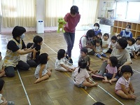 1歳りす組と2歳うさぎ組の子どもたちに、カエルのぴょんたが話しかけている写真
