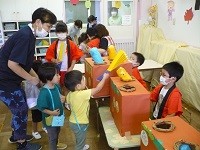 2歳児クラスの子どもが、らいおん組のもぐらたたきコーナーで遊んでいる写真