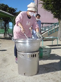 園長先生がかまどで芋汁を作っている写真